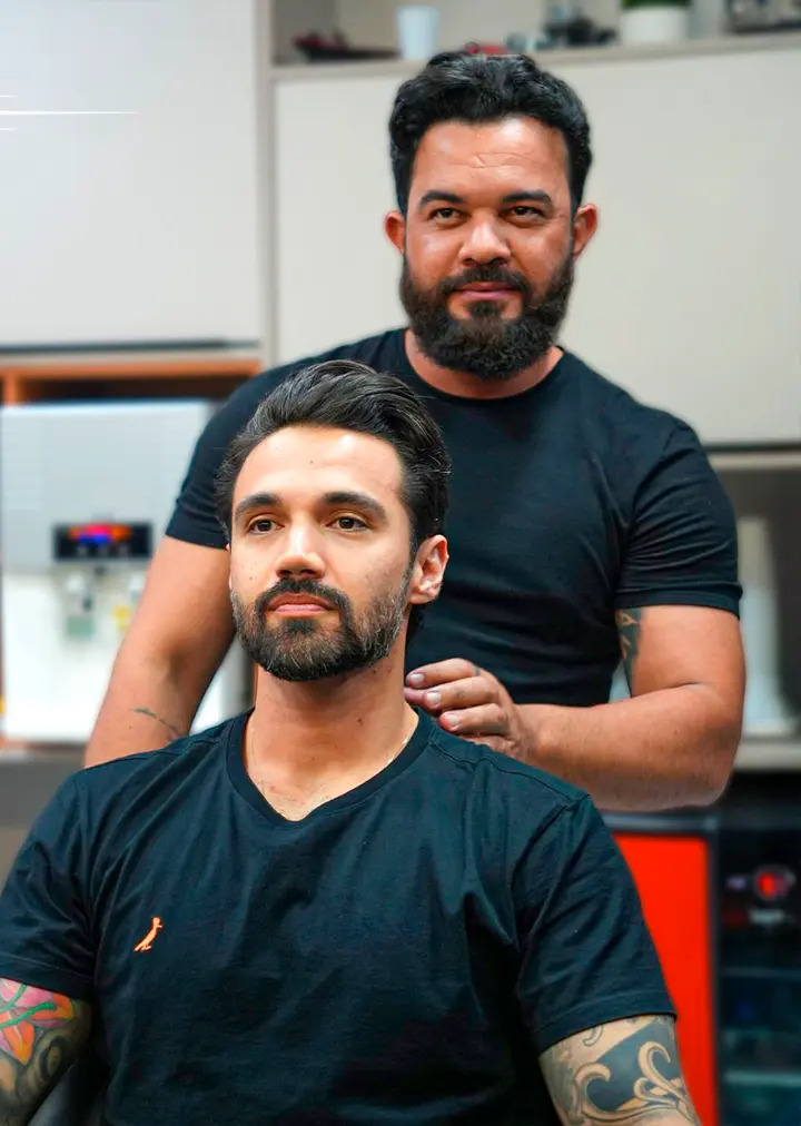 Barbeiro e cliente após o cuidado com a barba
