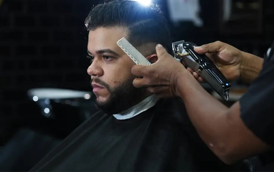 Barbeiro realizando um corte com máquina
